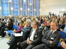 Saal mit vielen Menschen in Stuhlreihen