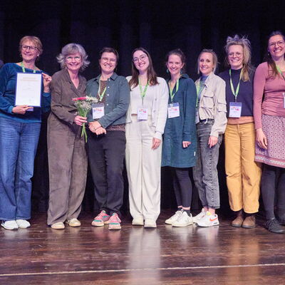 Gruppe von 10 Frauen auf einer Bühne, alle freuen sich