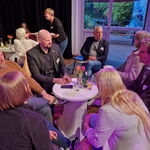 Verschiedene Männer und Frauen sitzen um einen Tisch und sprechen