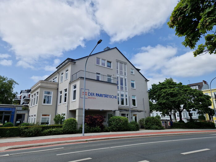 Haus an einer Straße mit Radweg. Logo Der Paritätische
