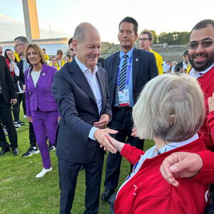 Bundeskanzler Scholz schüttelt einer Athletin die Hand