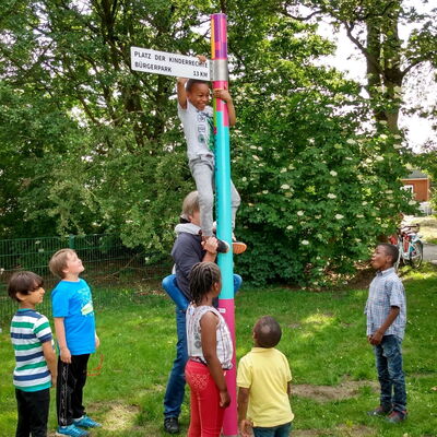 Kinder um einen Wegweiser "Platz der Kinderrechte"