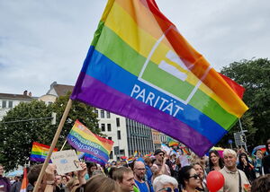 Demozug in Bremen, Menschen halten ein Banner, bunte Parität-Flagge