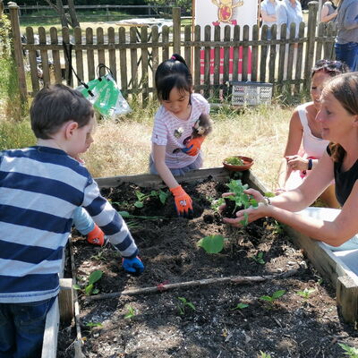 Kinder mit Erzieherin an einem Hochbeet