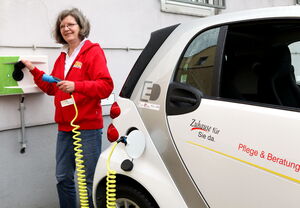 Frau lädt einen E-Smart des ASB Bremen an Ladestation auf.