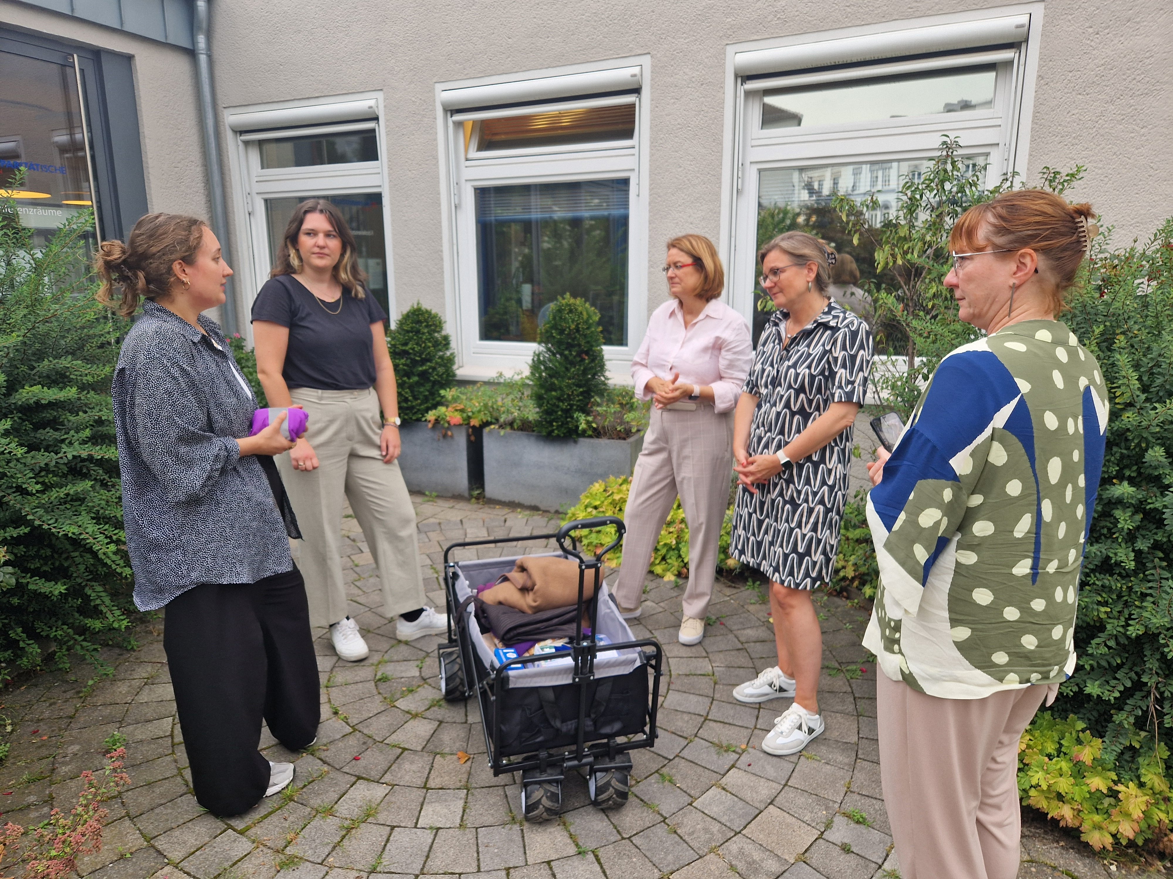 5 Frauen stehen um einen Bollerwagen