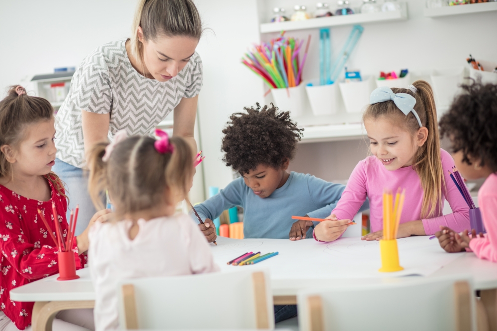 Pädagogin mit Kindern beim gemeinsamen Malen und Zeichnen